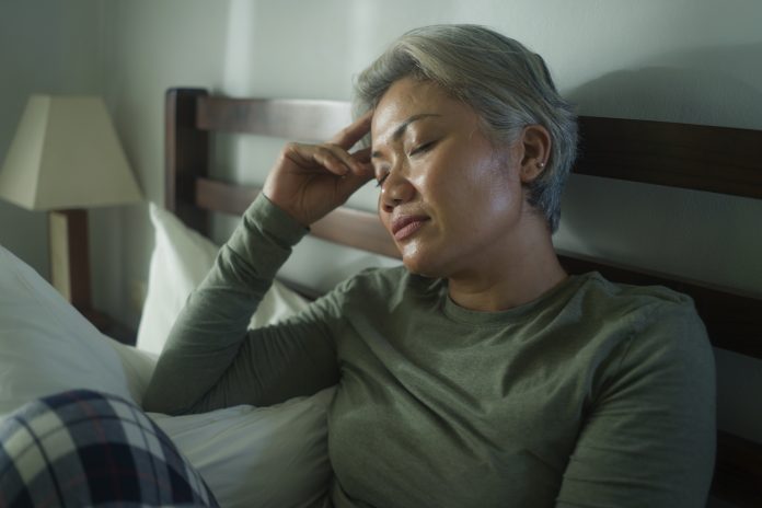 attractive middle aged woman with grey hair sad and depressed in bed feeling scared and lonely thinking worried about covid-19 virus pandemic during home lockdown