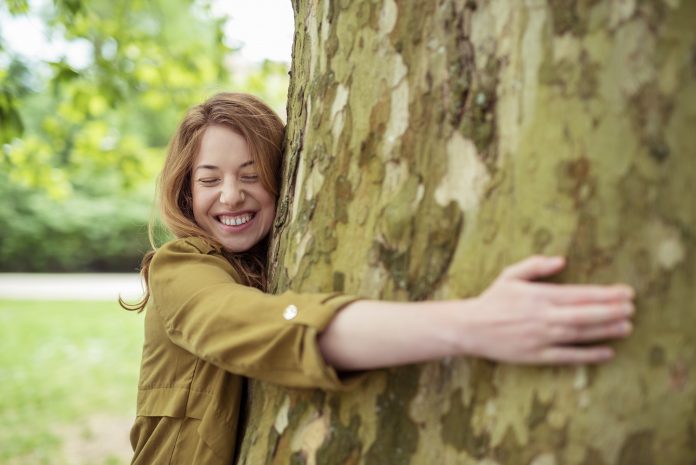 Cheerful Teen Girl Hugging Huge Tree Trunk