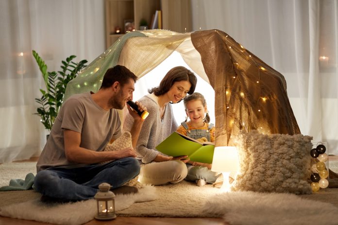 happy family reading book in kids tent at home